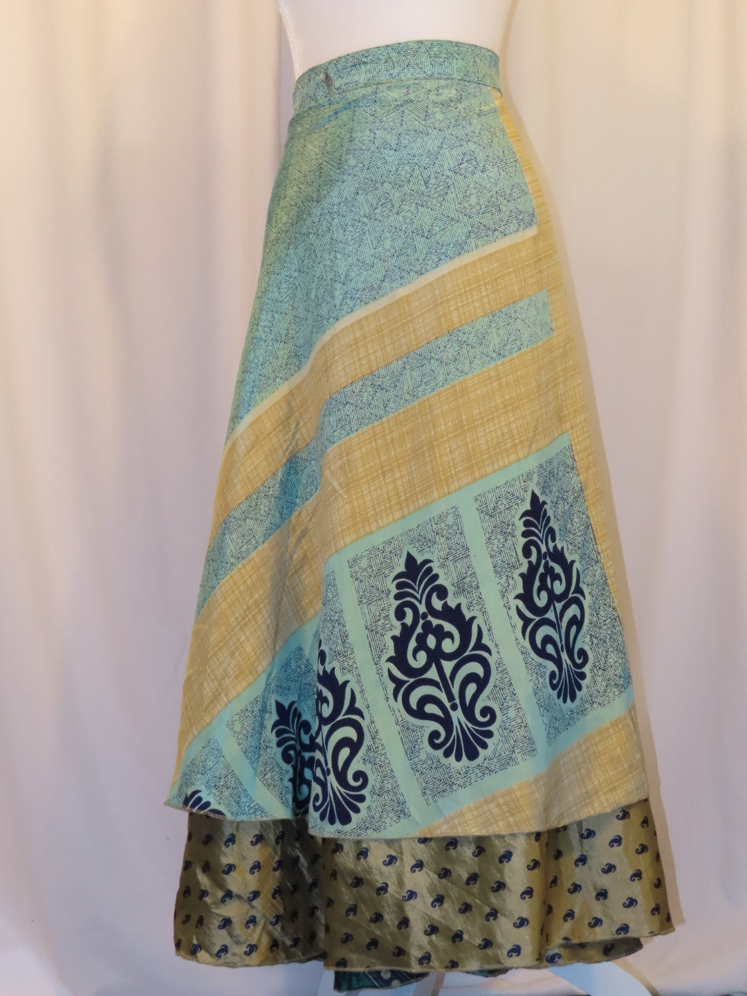 A long skirt with a combination of blue, beige, and green colors, featuring floral and geometric patterns.