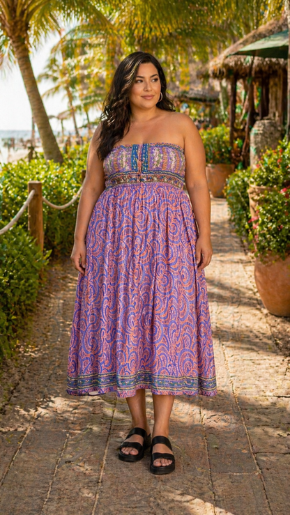 Woman in a strapless dress standing on a tropical path with plants and a hut in the background.